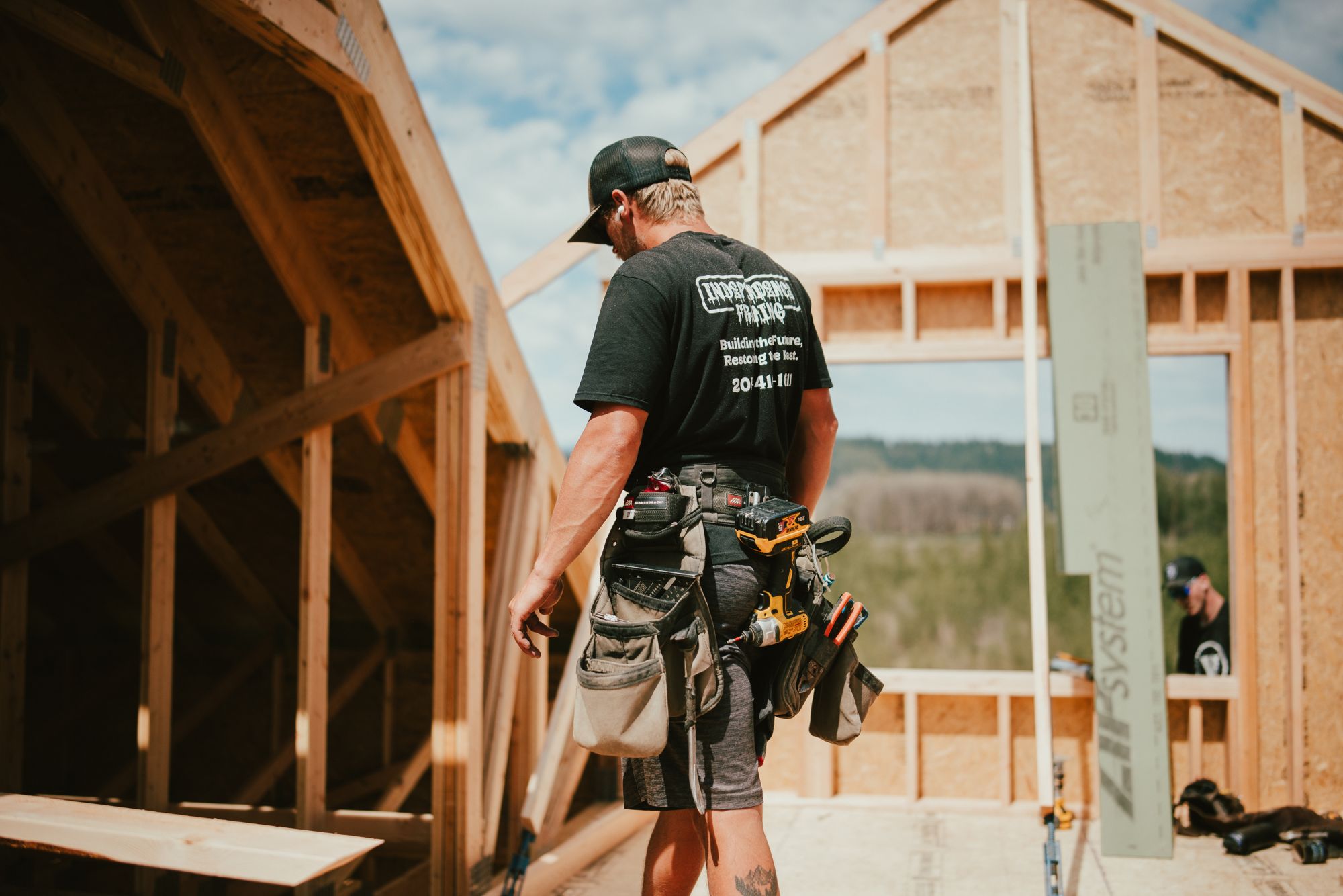 An IB carpenter inside the framing, with the valley through the window